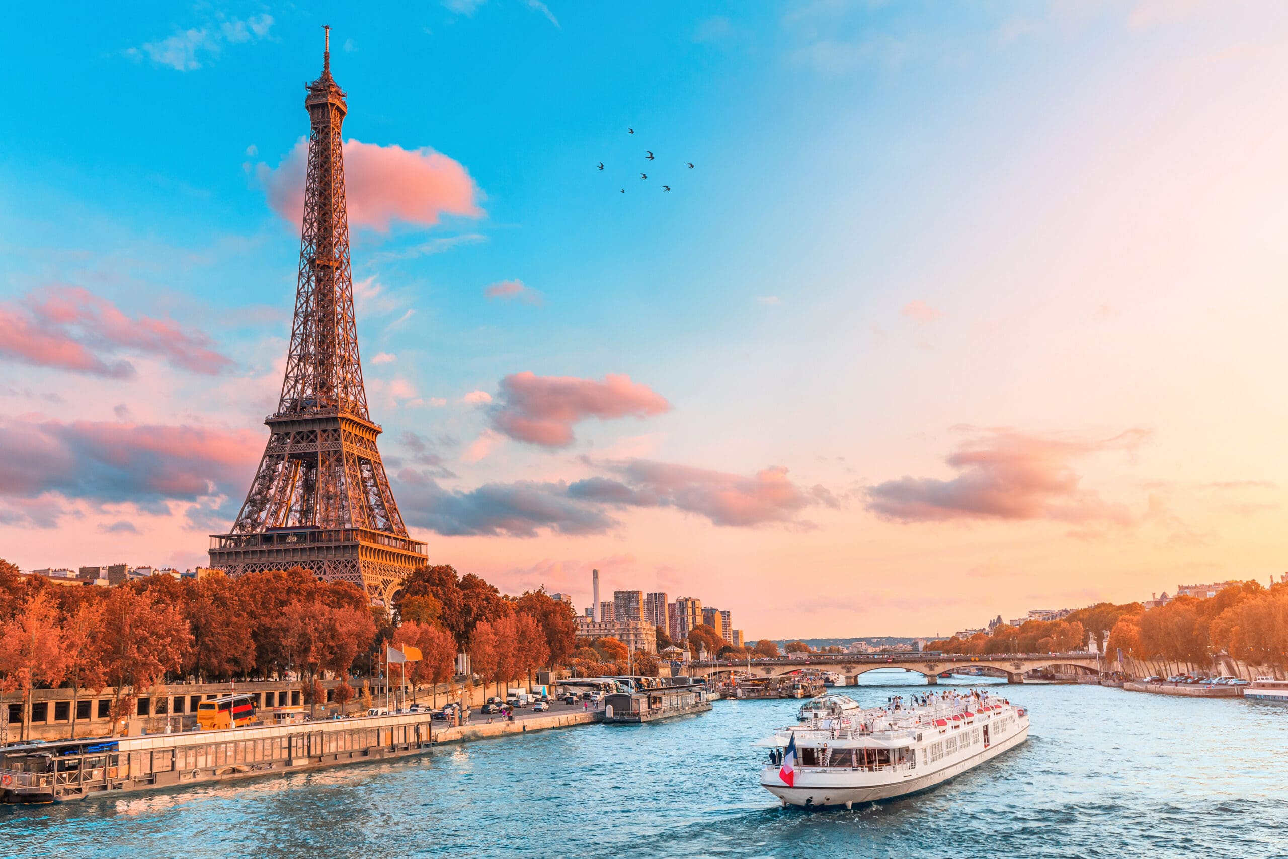 The main attraction of Paris and all of Europe is the Eiffel tower in the rays of the setting sun on the bank of Seine river with cruise tourist ships, France
