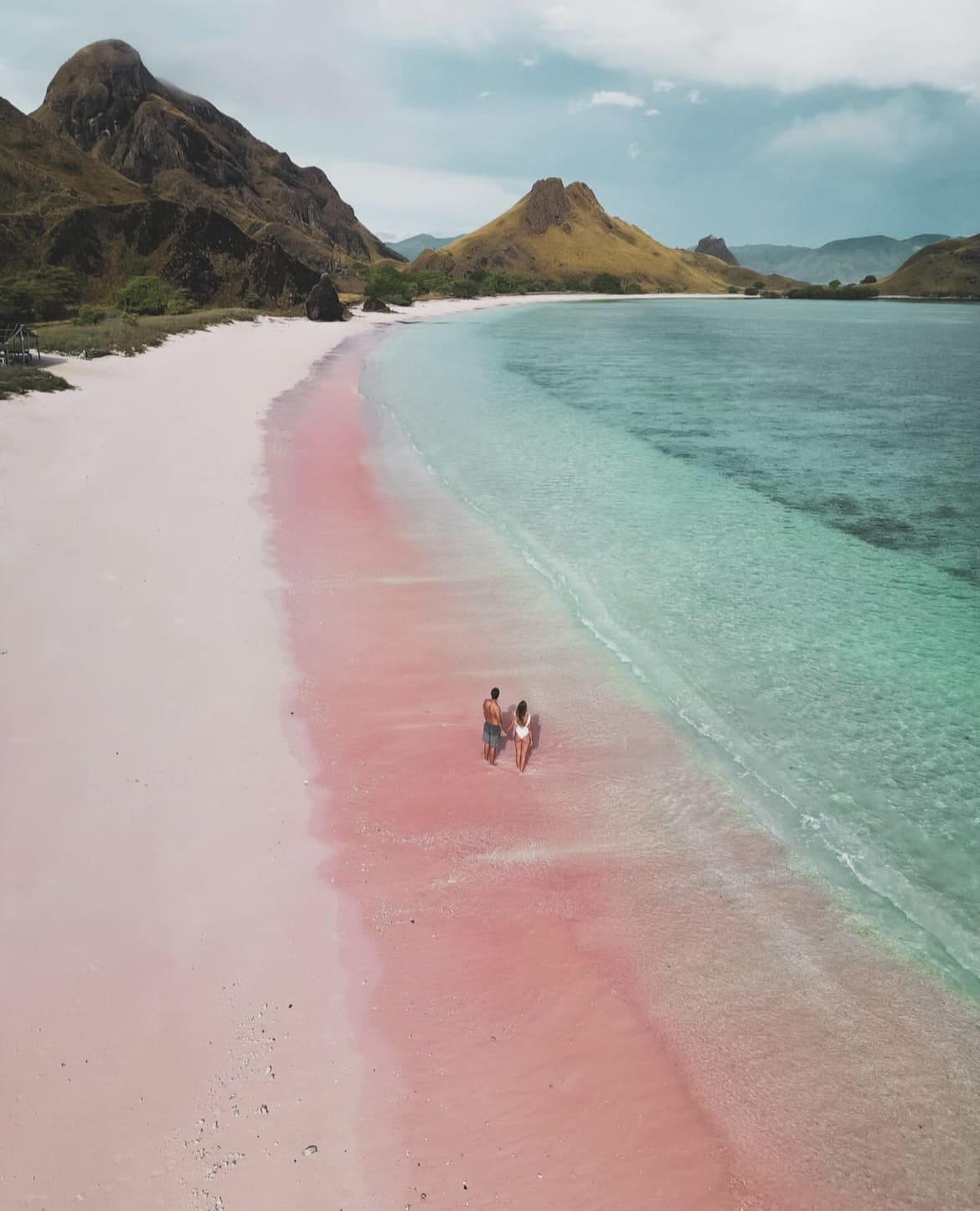 A couple walk along the Pink beach, Komodo Island