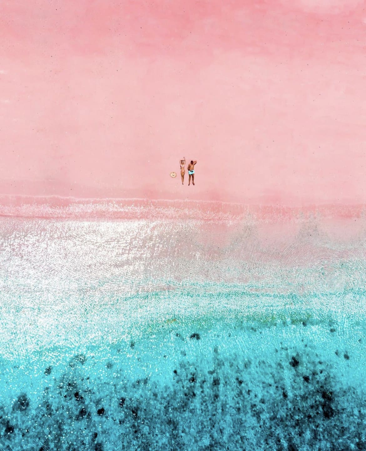 Couple lying on the shore at Pink Beach, Flores