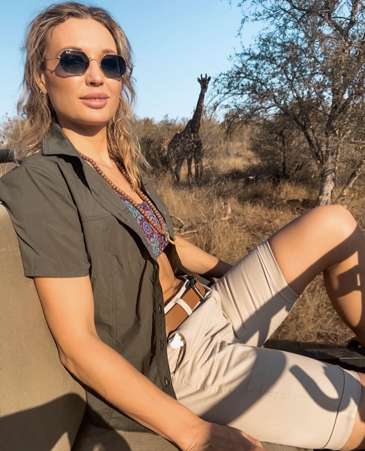 Woman showing off her safari outfit in front of a giraffe