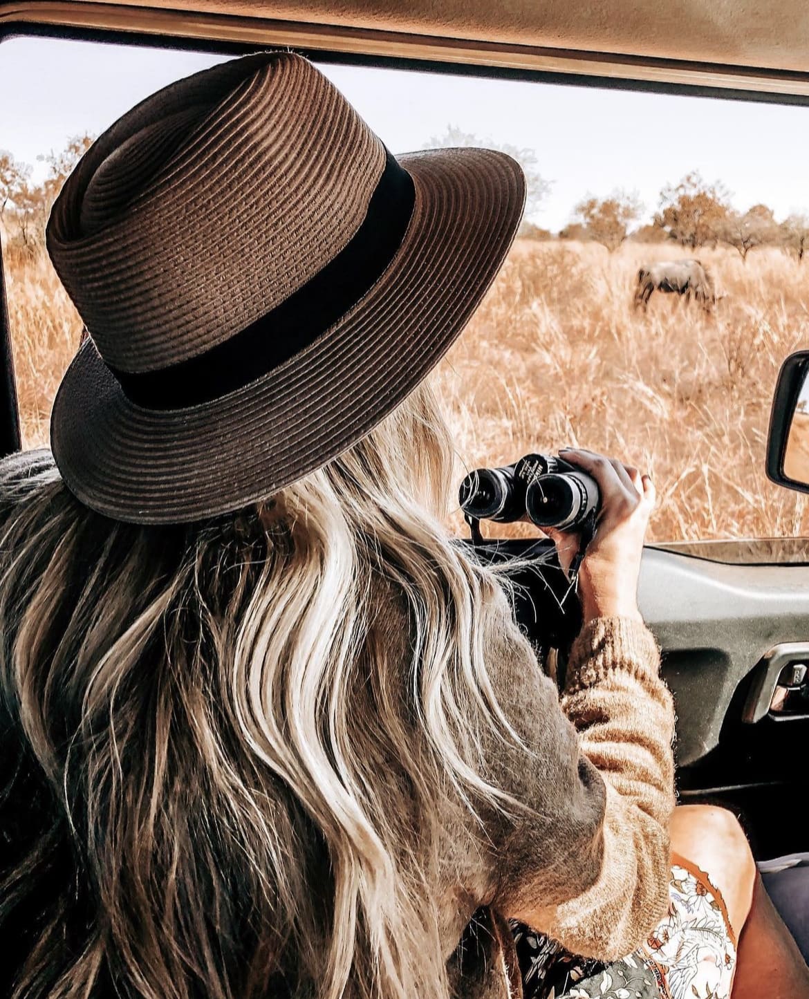 Woman using binoculars while on safari